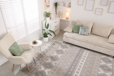 Photo of Comfortable sofa and stylish rug in room, above view. Interior design