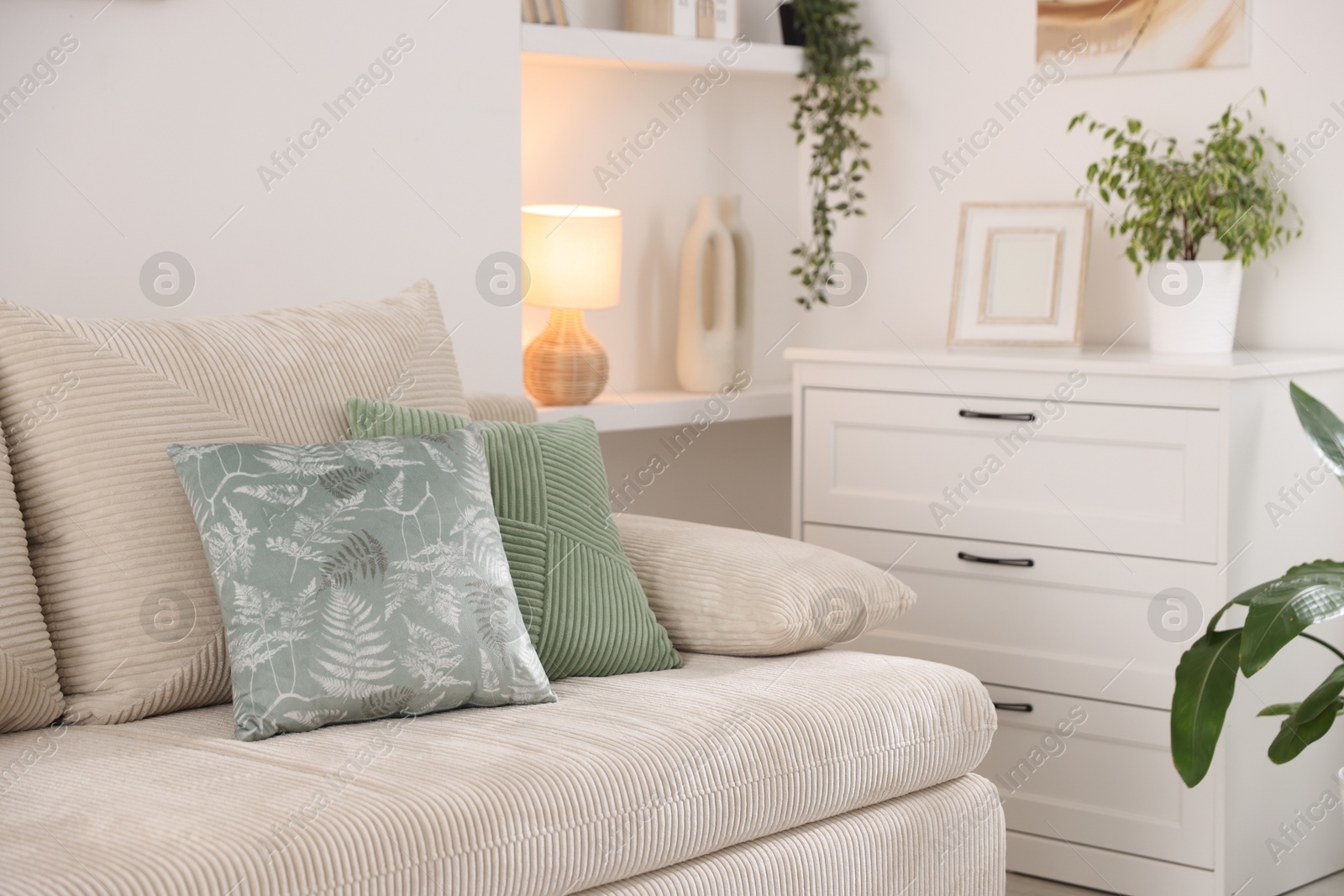 Photo of Sofa with cushions and chest of drawers indoors