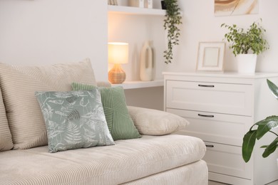 Photo of Sofa with cushions and chest of drawers indoors