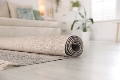 Photo of New rolled rug on floor at home, closeup