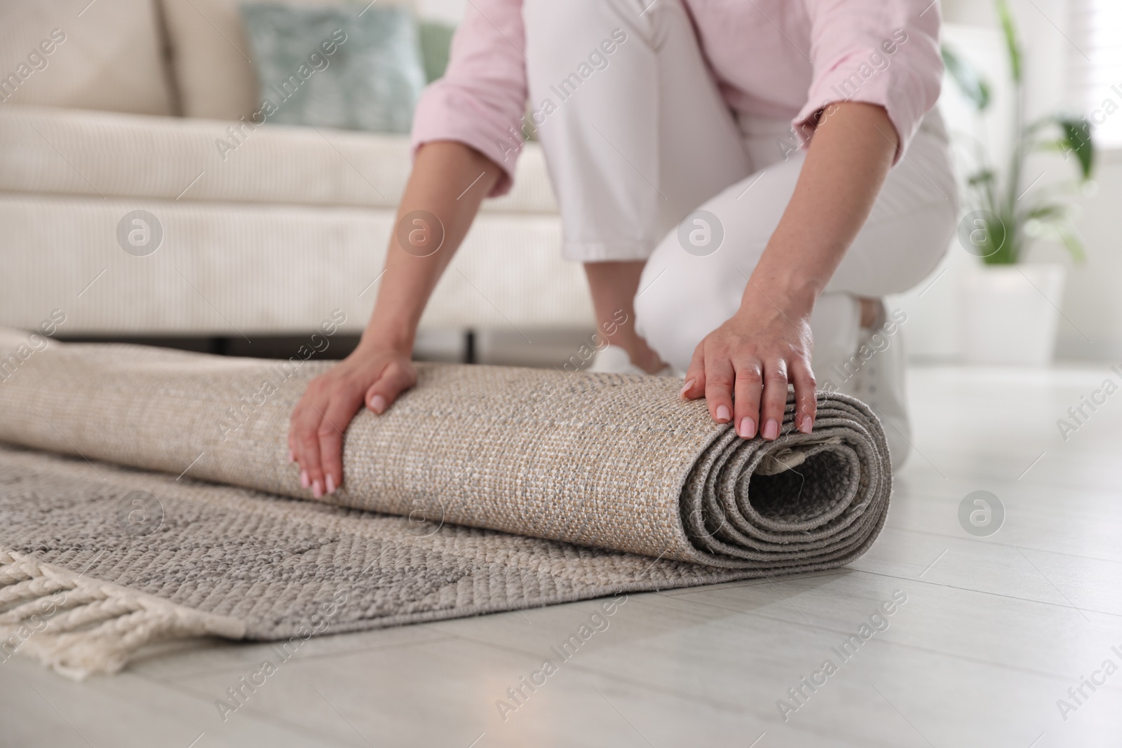 Woman putting new rug on floor at home, closeup Photo of Woman putting new rug on floor at home, closeup