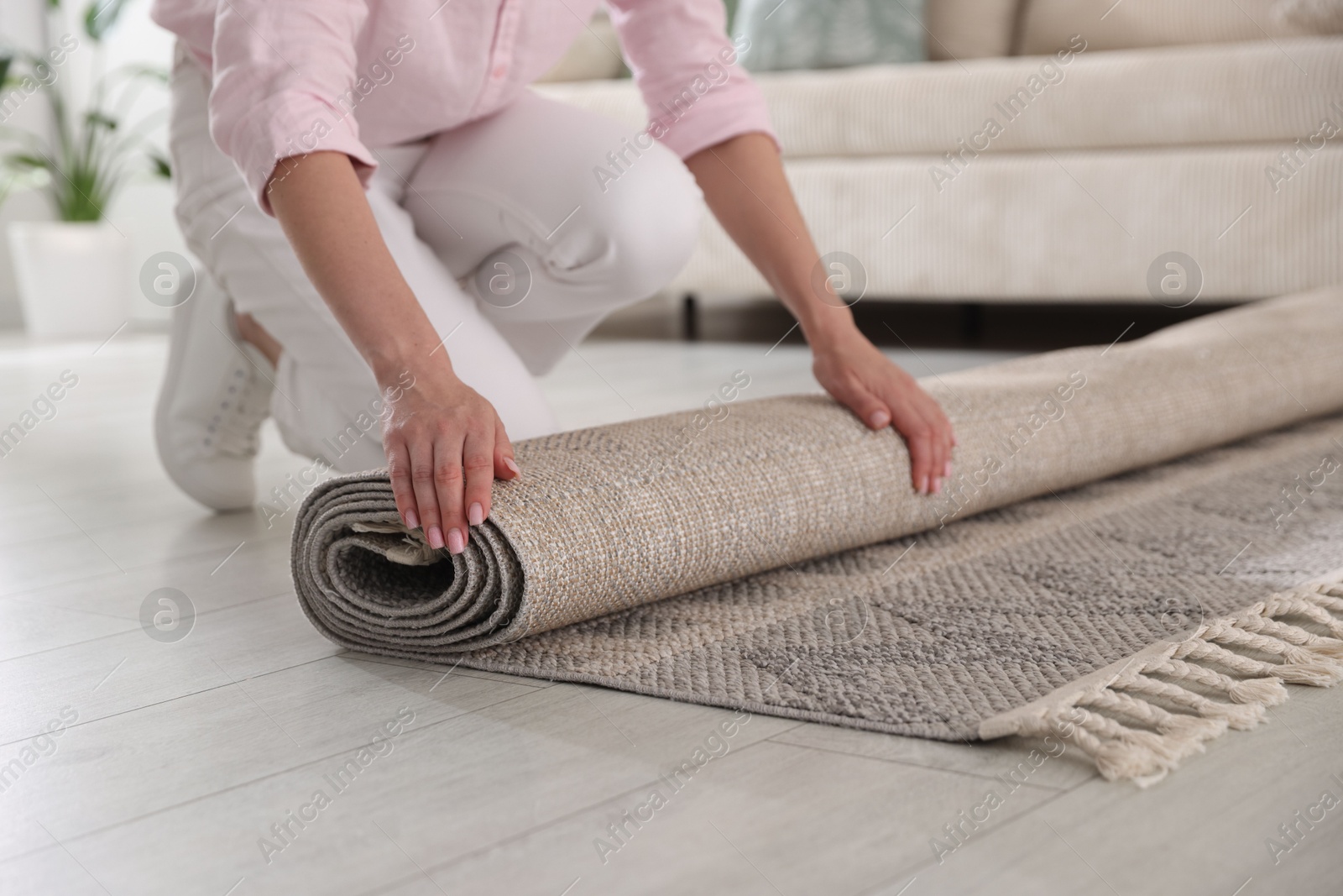 Woman putting new rug on floor at home, closeup Photo of Woman putting new rug on floor at home, closeup