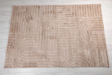 Photo of Stylish rug with pattern on light wooden floor, top view