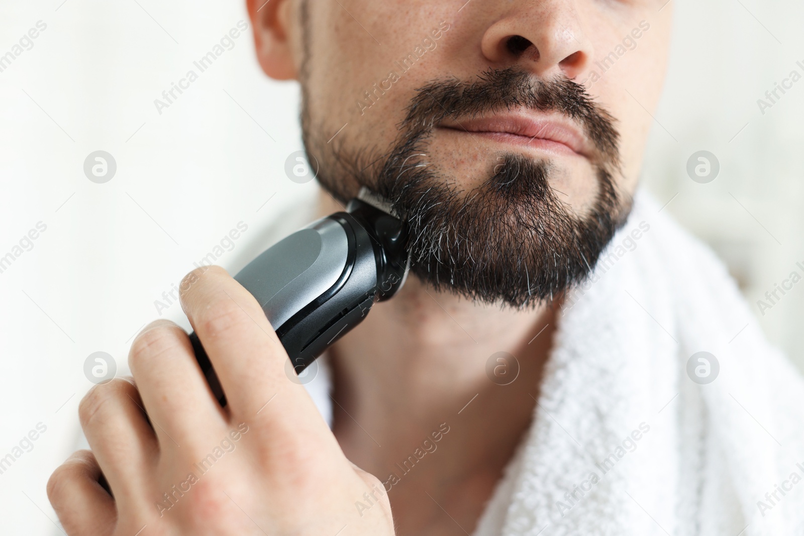 Man shaving with trimmer at home, closeup Photo of Man shaving with trimmer at home, closeup