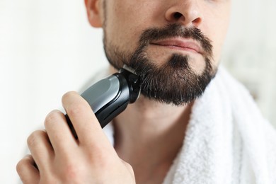 Photo of Man shaving with trimmer at home, closeup