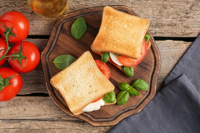 Photo of Tasty sandwiches with mozzarella cheese, tomatoes and basil on wooden table, flat lay