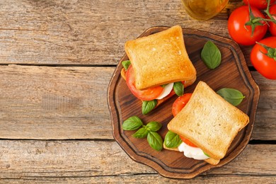 Photo of Tasty sandwiches with mozzarella cheese, tomatoes and basil on wooden table, flat lay. Space for text