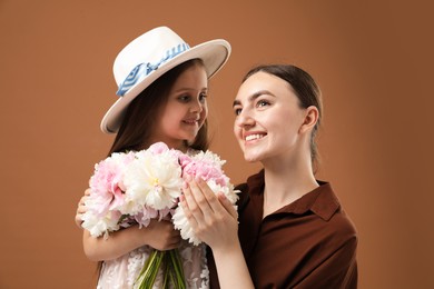 Photo of Mother and her daughter with bouquet of beautiful peonies on brown background
