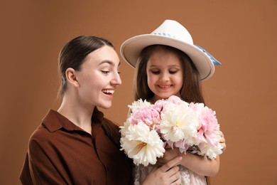 Photo of Mother and her daughter with bouquet of beautiful peonies on brown background