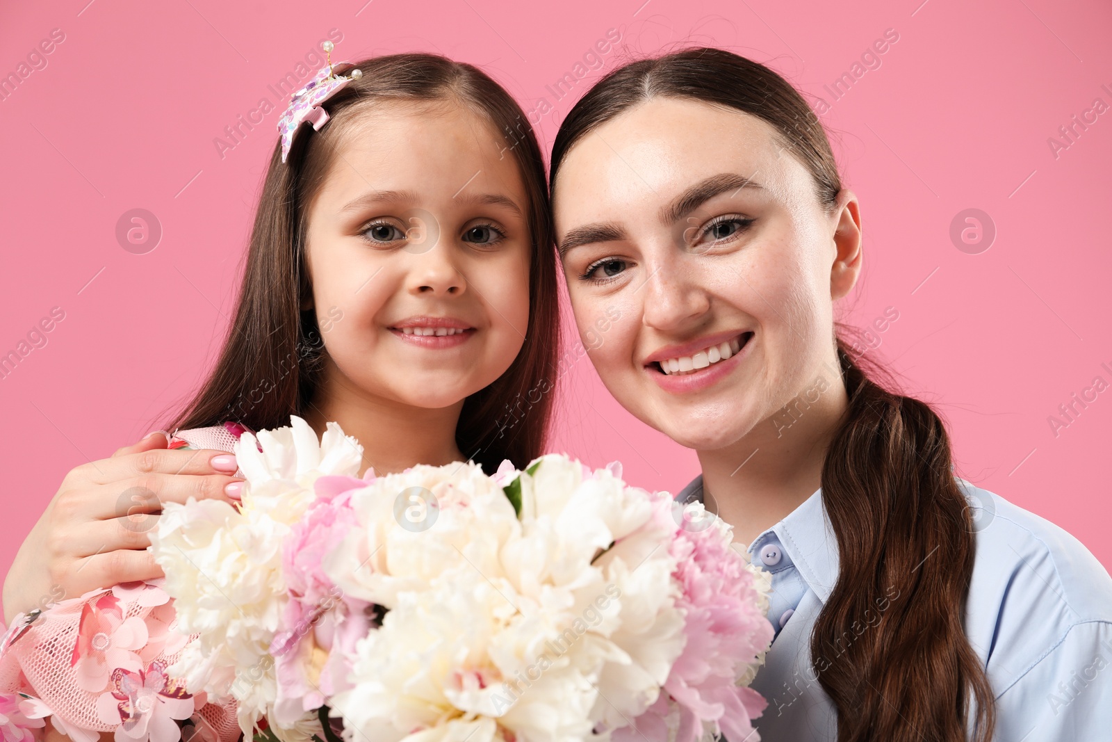 Mother and her daughter with bouquet of beautiful peonies on pink background Photo of Mother and her daughter with bouquet of beautiful peonies on pink background