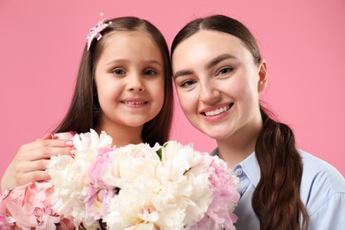 Photo of Mother and her daughter with bouquet of beautiful peonies on pink background