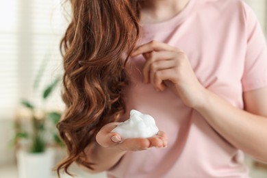 Photo of Teenage girl with hair mousse at home, closeup