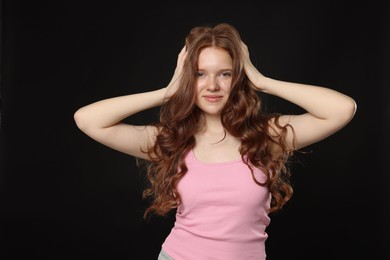 Photo of Portrait of beautiful teenage girl with healthy wavy hair on black background