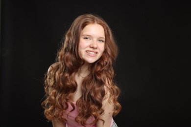 Photo of Portrait of smiling teenage girl with healthy wavy hair on black background