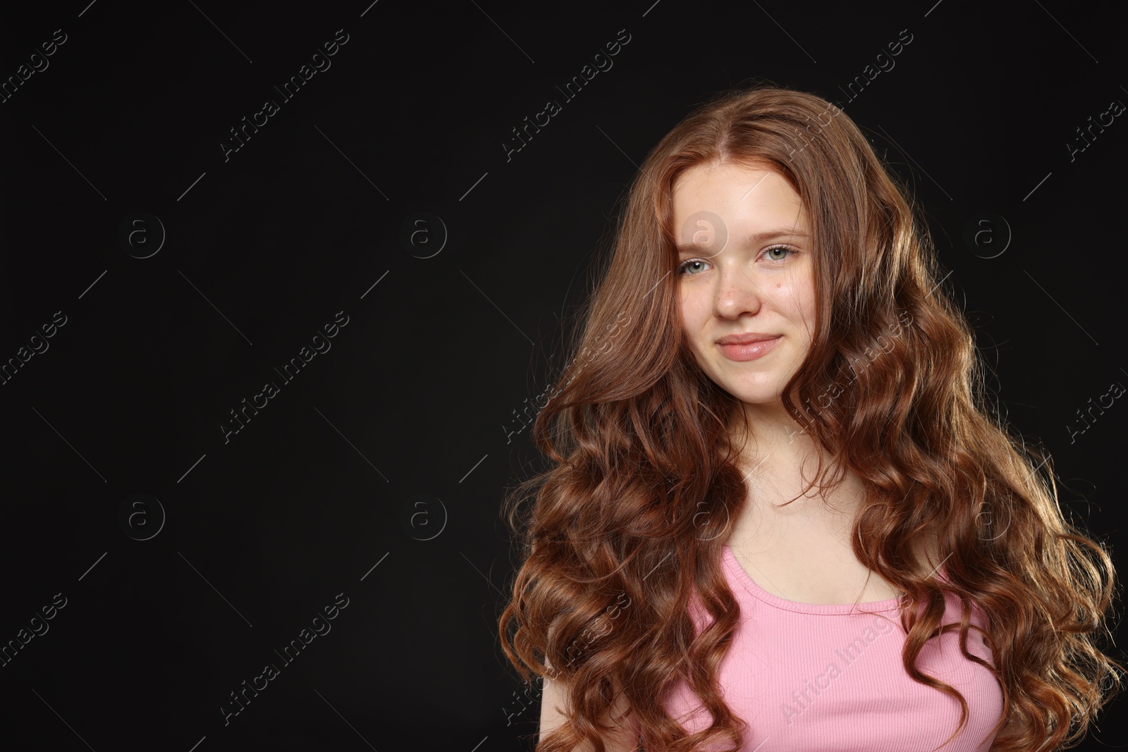 Beautiful teenage girl with healthy wavy hair on black background. Space for text Photo of Beautiful teenage girl with healthy wavy hair on black background. Space for text