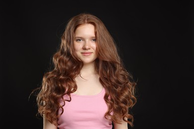 Photo of Portrait of beautiful teenage girl with healthy wavy hair on black background