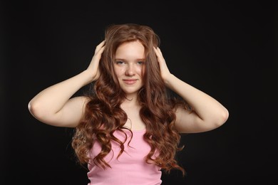 Photo of Portrait of beautiful teenage girl with healthy wavy hair on black background