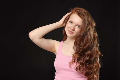 Photo of Portrait of beautiful teenage girl with healthy wavy hair on black background
