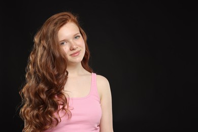 Photo of Beautiful teenage girl with healthy wavy hair on black background. Space for text