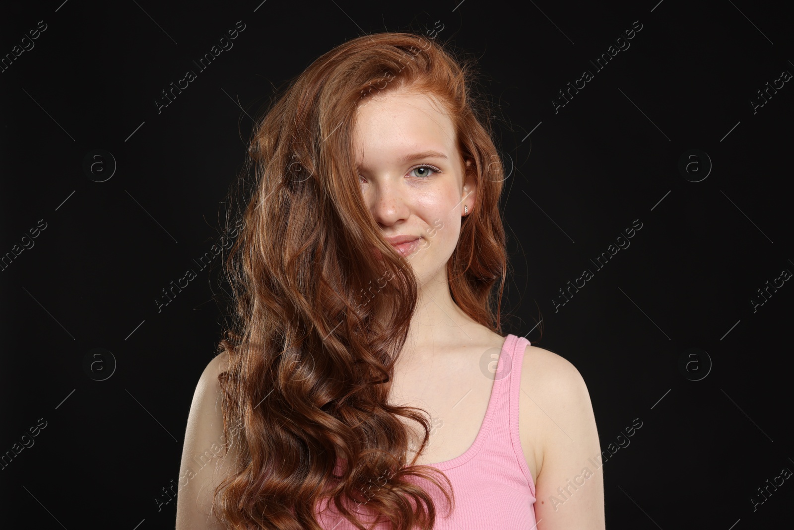 Portrait of beautiful teenage girl with healthy wavy hair on black background Photo of Portrait of beautiful teenage girl with healthy wavy hair on black background