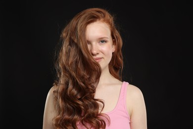 Photo of Portrait of beautiful teenage girl with healthy wavy hair on black background