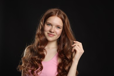Photo of Portrait of beautiful teenage girl with healthy wavy hair on black background