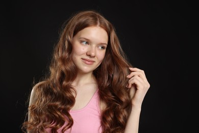 Photo of Portrait of beautiful teenage girl with healthy wavy hair on black background