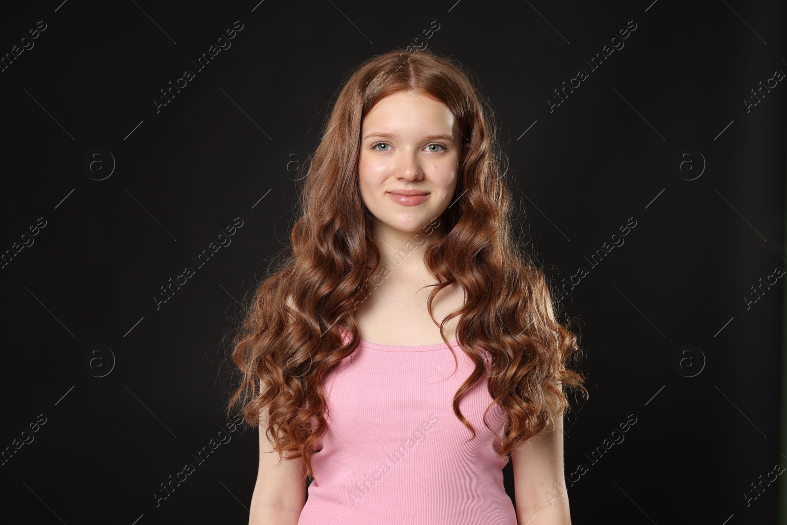 Portrait of beautiful teenage girl with healthy wavy hair on black background Photo of Portrait of beautiful teenage girl with healthy wavy hair on black background