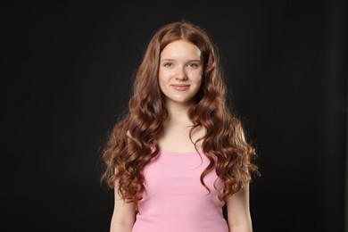Photo of Portrait of beautiful teenage girl with healthy wavy hair on black background