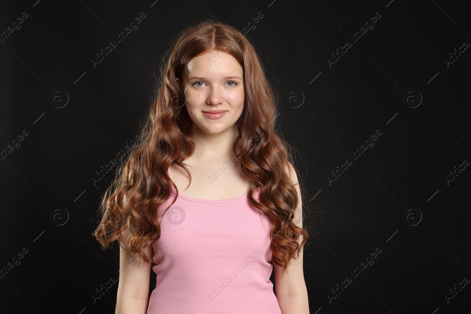 Portrait of beautiful teenage girl with healthy wavy hair on black background Photo of Portrait of beautiful teenage girl with healthy wavy hair on black background