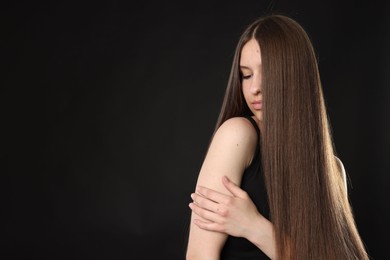 Photo of Beautiful teenage girl with healthy long hair on black background. Space for text
