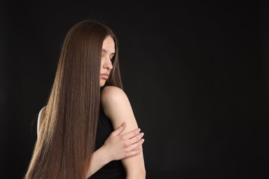 Photo of Beautiful teenage girl with healthy long hair on black background. Space for text