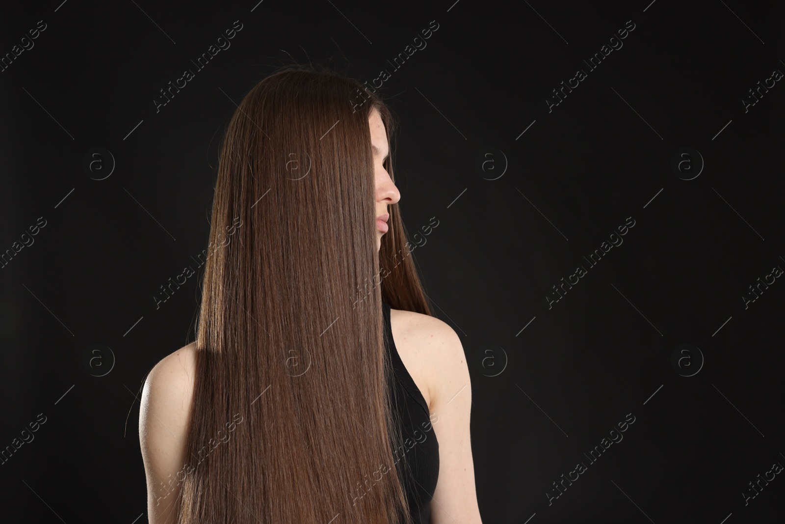 Beautiful teenage girl with healthy long hair on black background. Space for text Photo of Beautiful teenage girl with healthy long hair on black background. Space for text