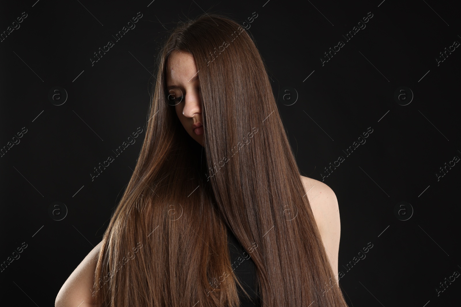 Beautiful teenage girl with healthy long hair on black background Photo of Beautiful teenage girl with healthy long hair on black background