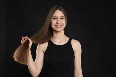 Photo of Portrait of smiling teenage girl with healthy long hair on black background