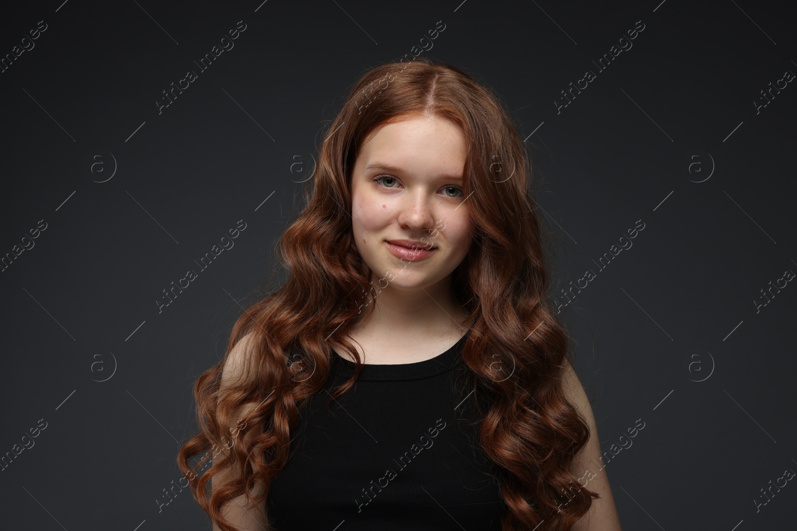 Portrait of beautiful teenage girl with healthy wavy hair on dark grey background Photo of Portrait of beautiful teenage girl with healthy wavy hair on dark grey background
