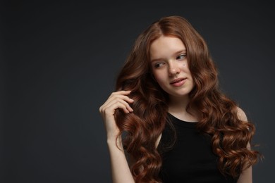 Photo of Portrait of beautiful teenage girl with healthy wavy hair on dark grey background. Space for text