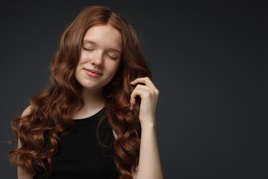 Photo of Beautiful teenage girl with healthy wavy hair on dark grey background. Space for text
