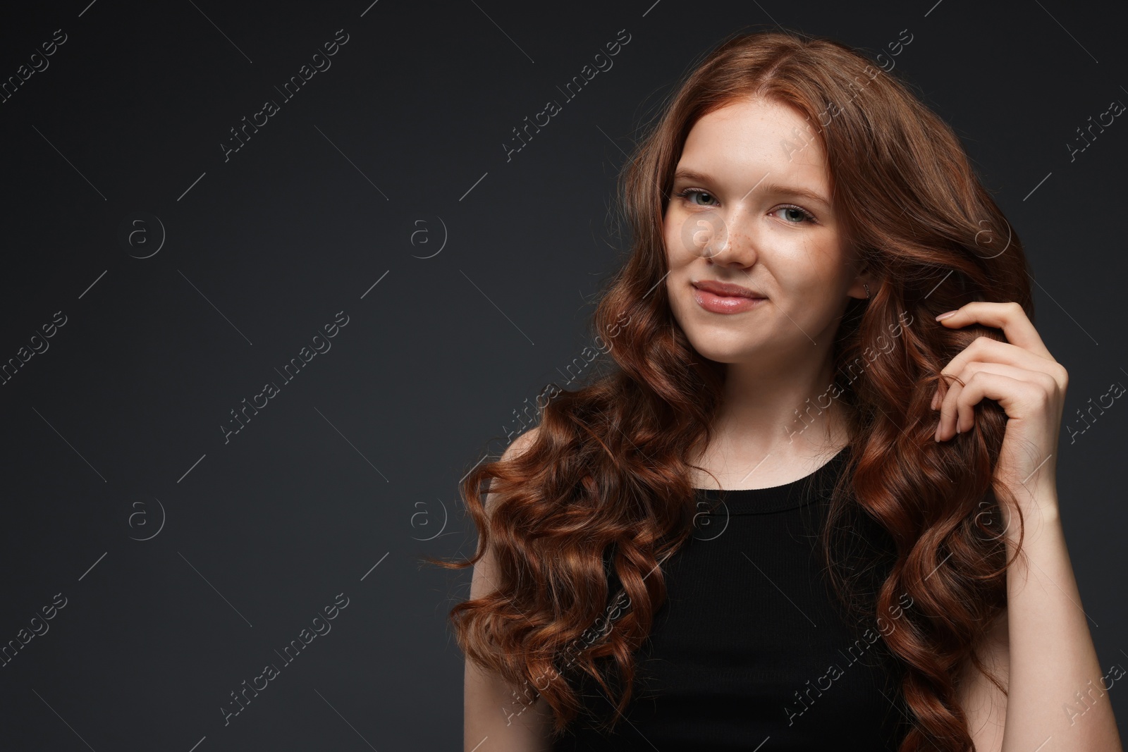 Portrait of beautiful teenage girl with healthy wavy hair on dark grey background. Space for text Photo of Portrait of beautiful teenage girl with healthy wavy hair on dark grey background. Space for text