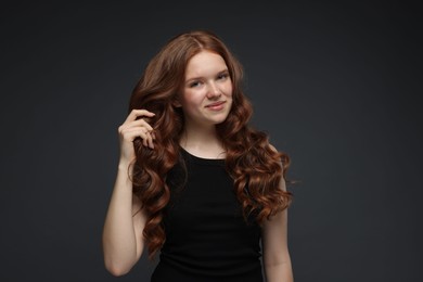 Photo of Portrait of beautiful teenage girl with healthy wavy hair on dark grey background