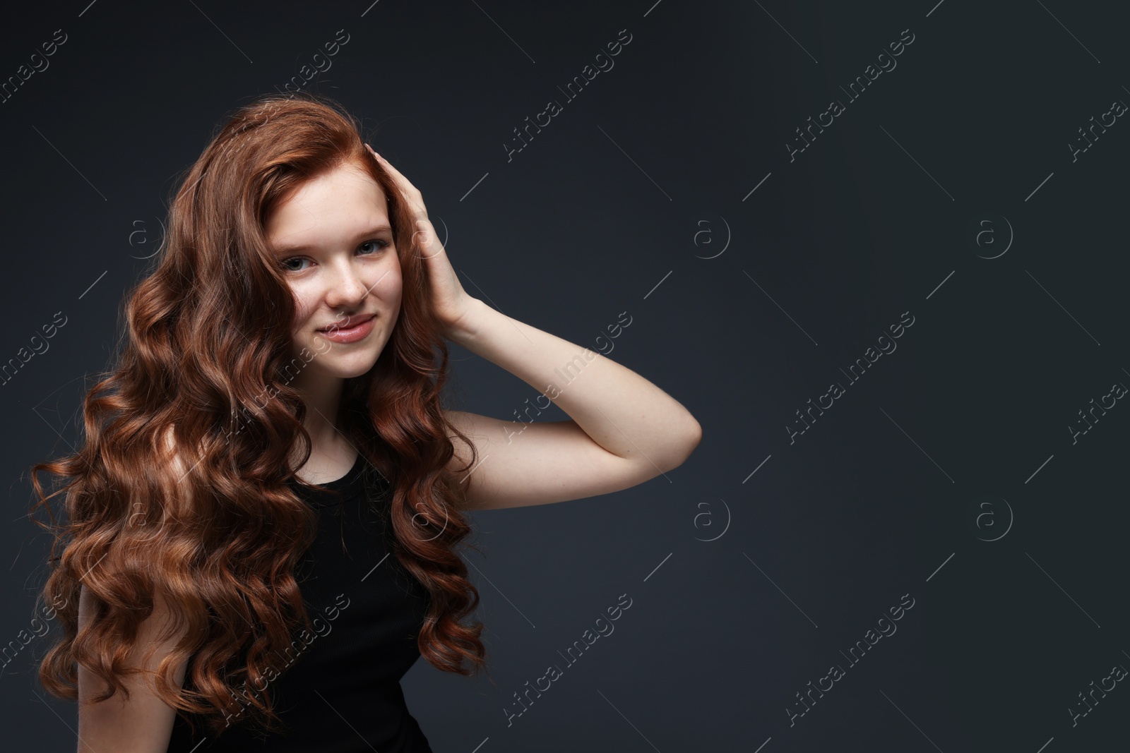 Portrait of beautiful teenage girl with healthy wavy hair on dark grey background. Space for text Photo of Portrait of beautiful teenage girl with healthy wavy hair on dark grey background. Space for text