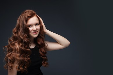 Photo of Portrait of beautiful teenage girl with healthy wavy hair on dark grey background. Space for text