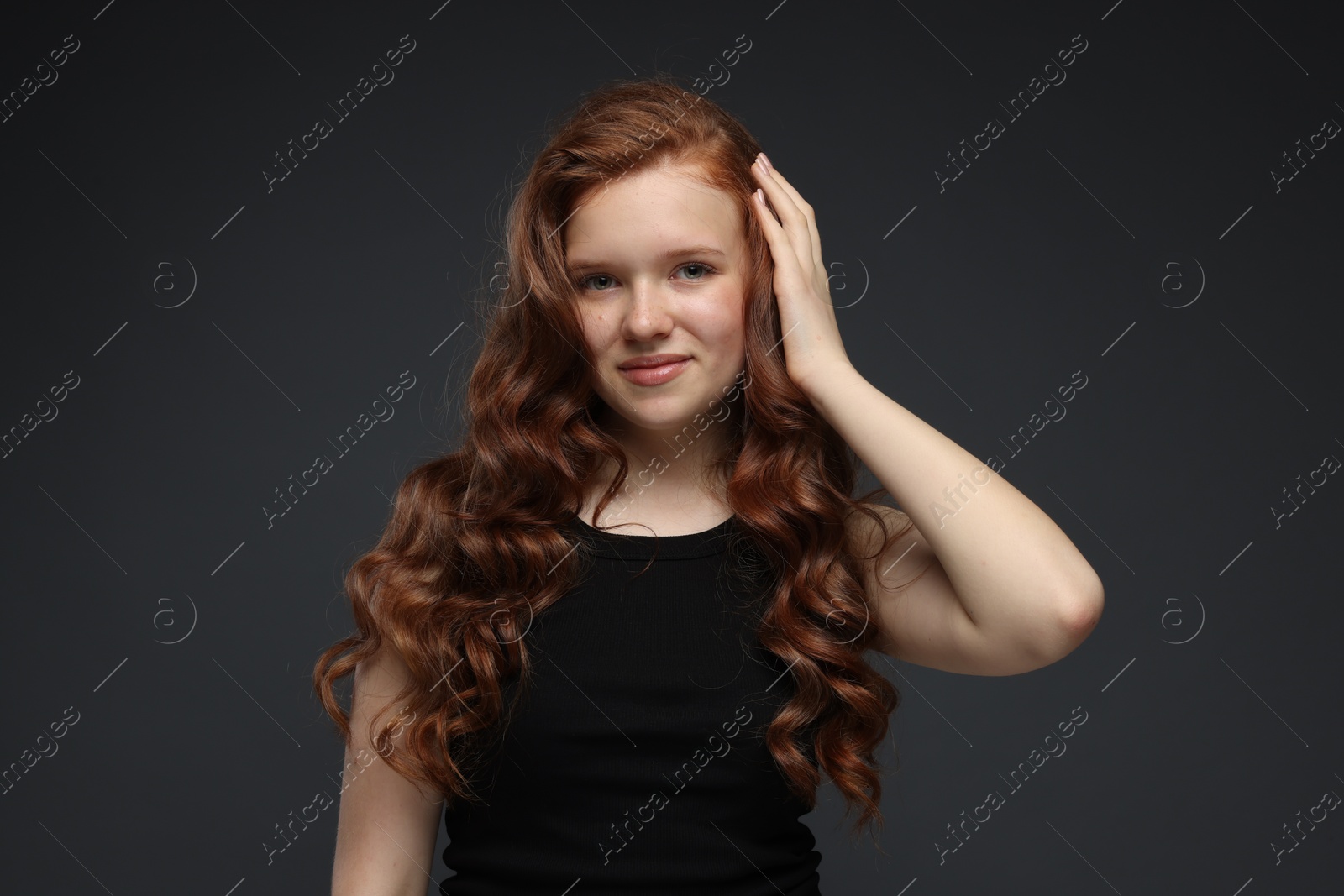 Portrait of beautiful teenage girl with healthy wavy hair on dark grey background Photo of Portrait of beautiful teenage girl with healthy wavy hair on dark grey background