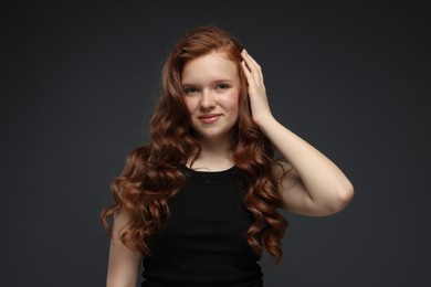 Photo of Portrait of beautiful teenage girl with healthy wavy hair on dark grey background