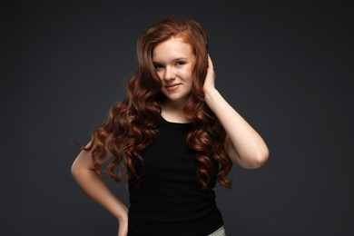Photo of Portrait of beautiful teenage girl with healthy wavy hair on dark grey background