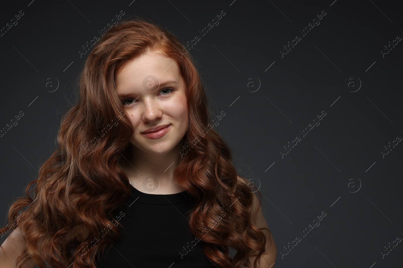 Portrait of beautiful teenage girl with healthy wavy hair on dark grey background. Space for text Photo of Portrait of beautiful teenage girl with healthy wavy hair on dark grey background. Space for text