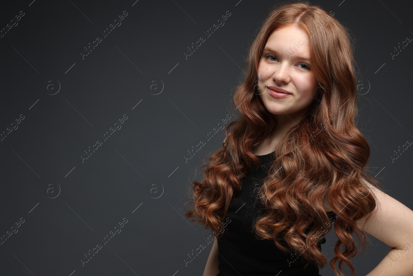 Portrait of beautiful teenage girl with healthy wavy hair on dark grey background. Space for text Photo of Portrait of beautiful teenage girl with healthy wavy hair on dark grey background. Space for text