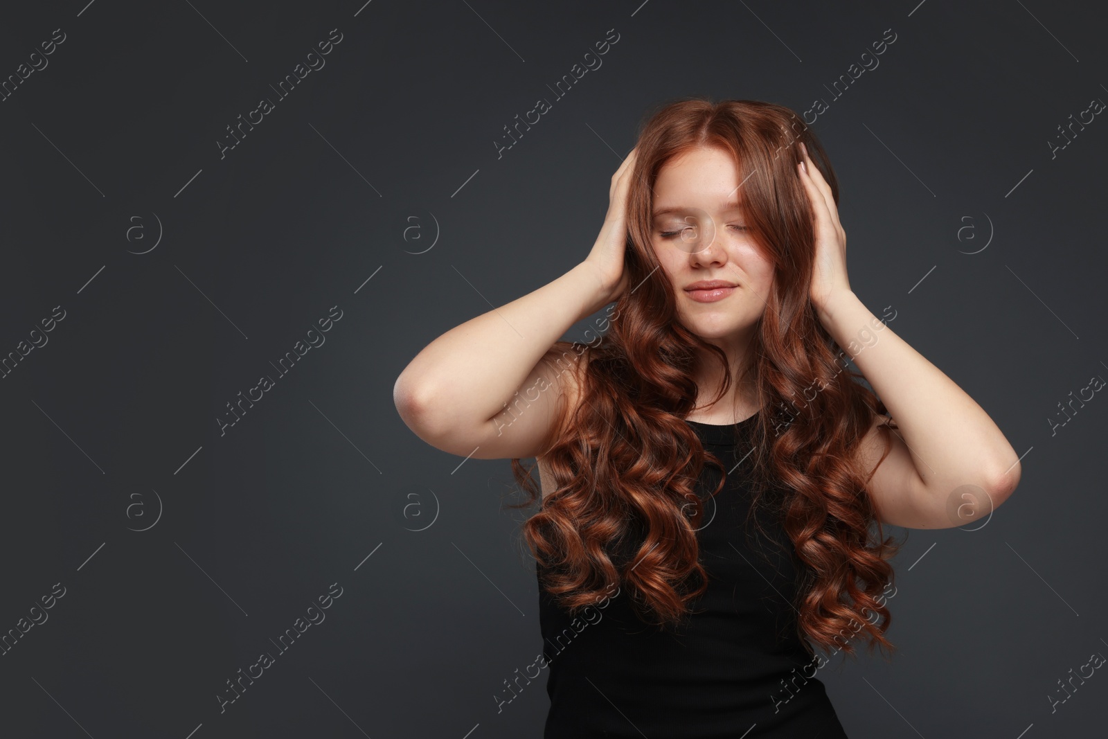 Beautiful teenage girl with healthy wavy hair on dark grey background. Space for text Photo of Beautiful teenage girl with healthy wavy hair on dark grey background. Space for text