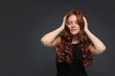 Photo of Beautiful teenage girl with healthy wavy hair on dark grey background. Space for text