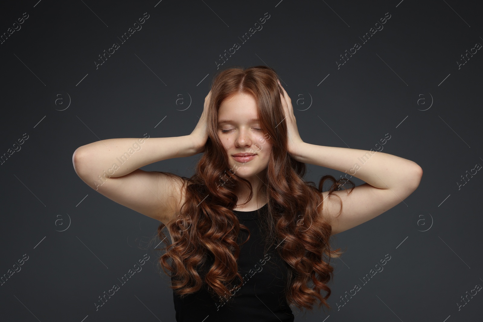 Beautiful teenage girl with healthy wavy hair on dark grey background Photo of Beautiful teenage girl with healthy wavy hair on dark grey background